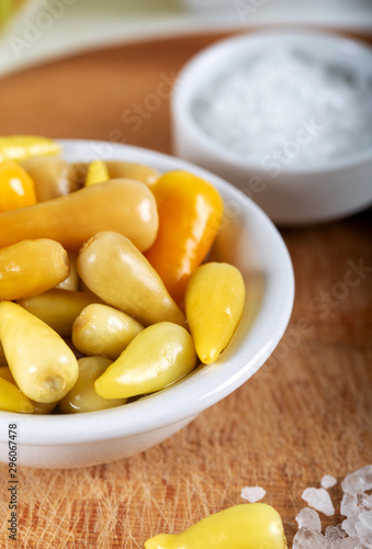 Marinated chili peppers with fresh green peppers on wooden background.