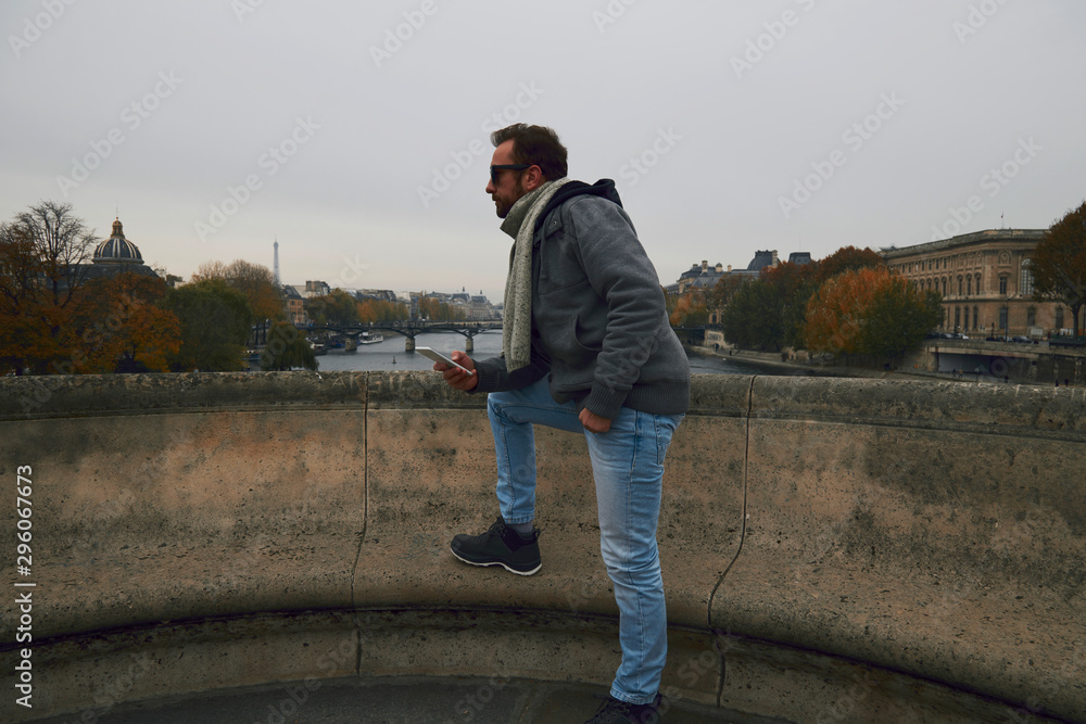 Handsome man enjoying in Paris while using cellphone.
