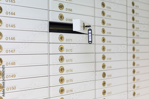 Storage with rows of individual deposit boxes in the bank. One door is open. Key in a lock