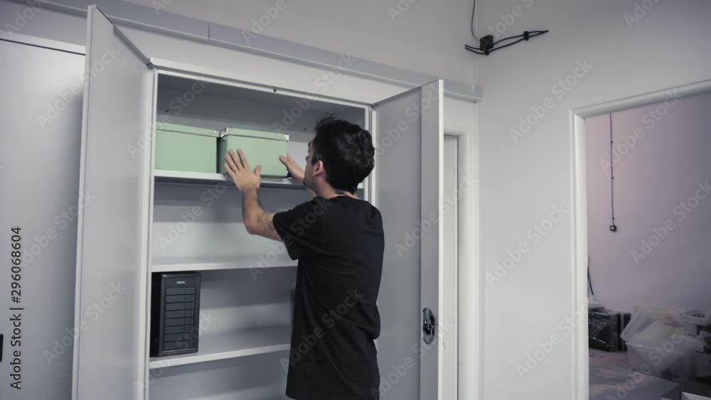 Man inserting cardboard box into cabinet Man inserting cardboard box into cabinet