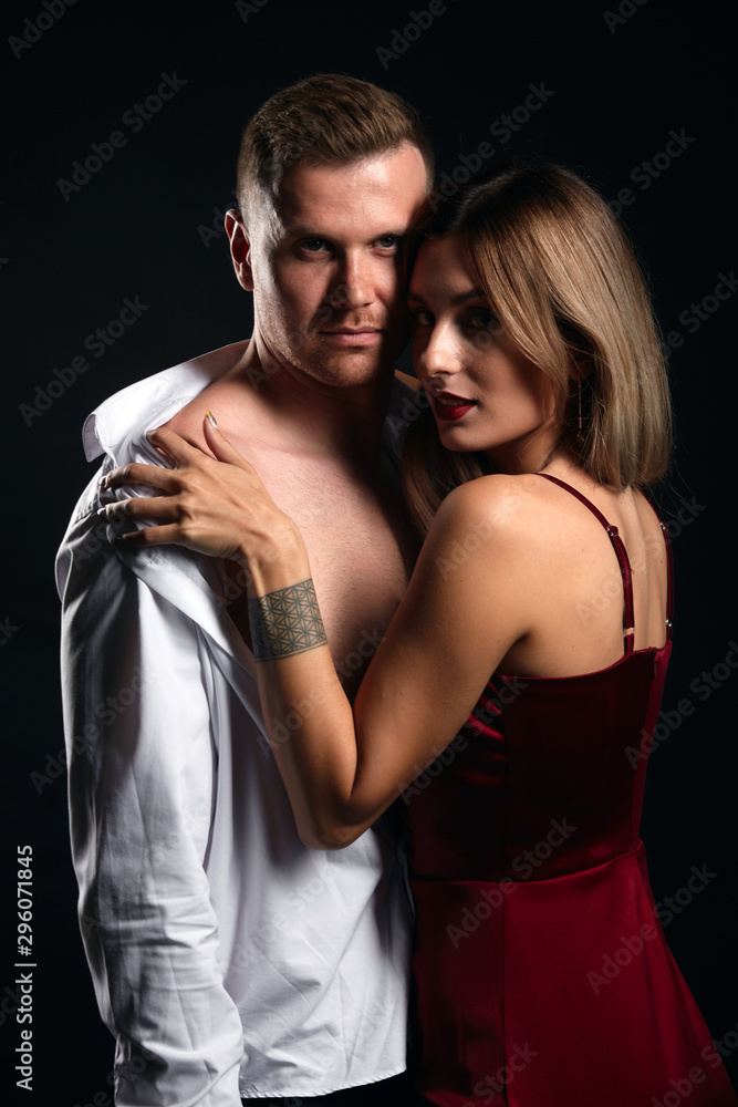 good looking man and woman fell in love, isolated black background, amorous habit, man is being undressed by a woman good looking man and woman fell in love, isolated black background, amorous habit, man is being undressed by a woman