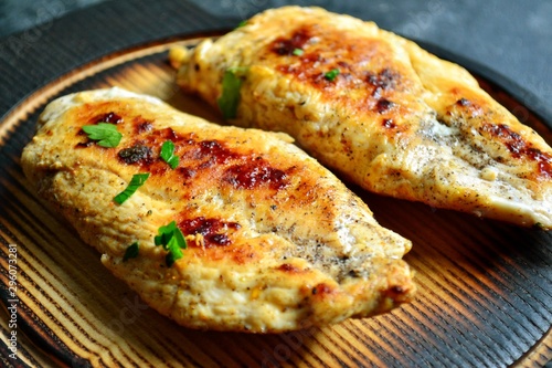 Grilled chicken breast. Chicken fillet with broccoli and mushrooms. Appetizing chicken meat on a wooden board on a dark background