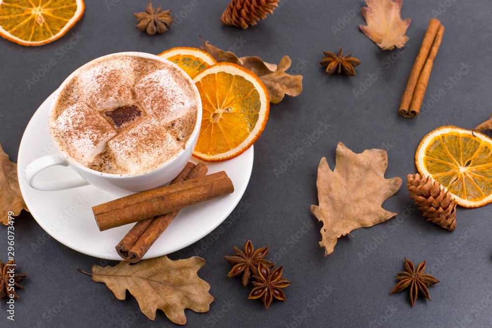 Cup of coffee with marshmallows and cocoa, leaves, dried oranges, cinnamon and star anise, gray stone background. Tasty hot autumn drink. Copy space. Cup of coffee with marshmallows and cocoa, leaves, dried oranges, cinnamon and star anise, gray stone background. Tasty hot autumn drink. Copy space.