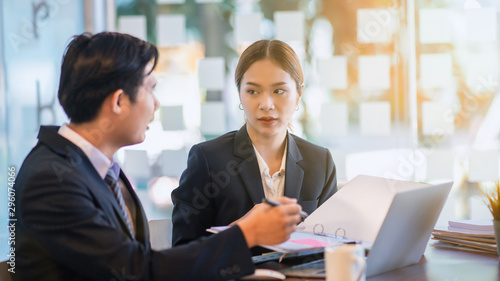 Team of two business people working together in workplace using laptop computer