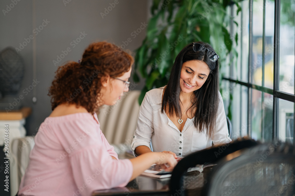Womans chatting and reading while they sitting in a cafe Womans chatting and reading while they sitting in a cafe