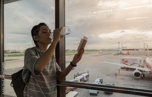 Cute girl eating water and see passports airport background. soft focas.