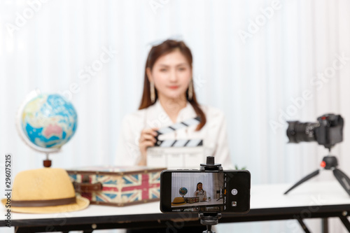 Young travel blogger girl reviewing in front of camera and recording video at home for vlog.