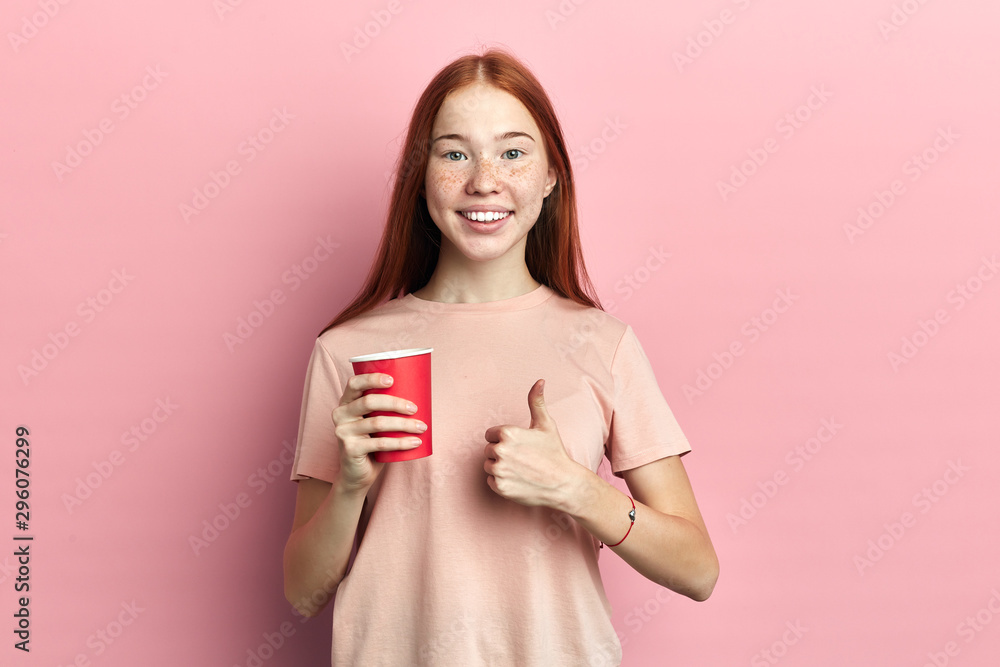 smiling young womanholding a cup of coffee over pink isolated background . girl showing ok sign.close up portrait, body language smiling young womanholding a cup of coffee over pink isolated background . girl showing ok sign.close up portrait, body language