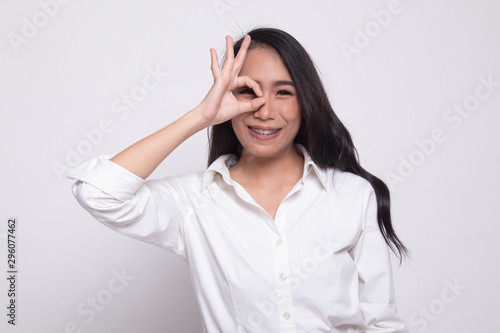 Beautiful young Asian woman show OK sign over her eye.