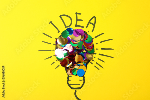 Drawn light bulb and multicolor glitter on yellow background. Good idea concept