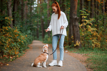 Beautiful young woman with playful young dog having fun outdoors, full length photo. lifestyle, pastime, leisure