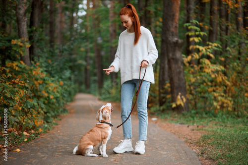 Beautiful young woman with playful young dog having fun outdoors, full length photo. lifestyle, pastime, leisure