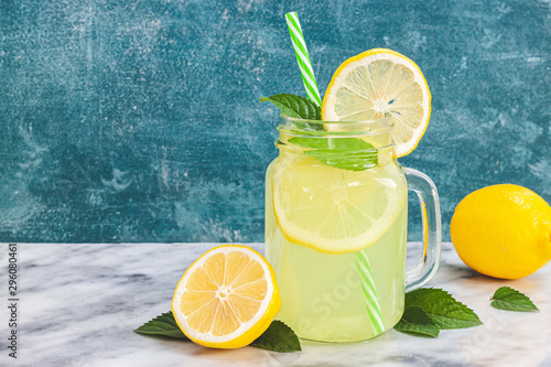 Fotografie Lemon lemonade in mason jar glass ofwith lemons and straw on tab