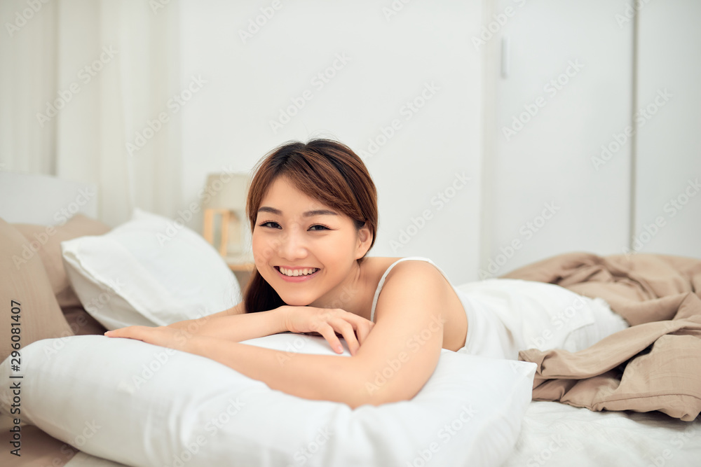 Young Asian woman lying in bed, knitted pillows around her. Young Asian woman lying in bed, knitted pillows around her.