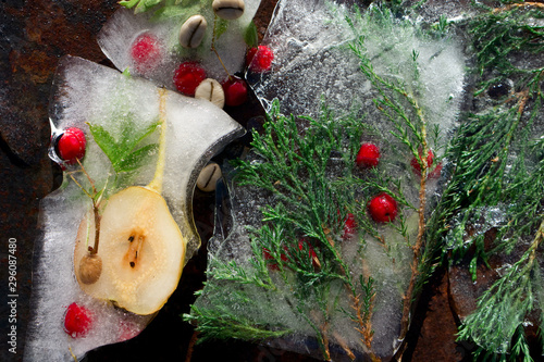 Background of red berry of hawthorn and twif of juniper  frozen in ice photo