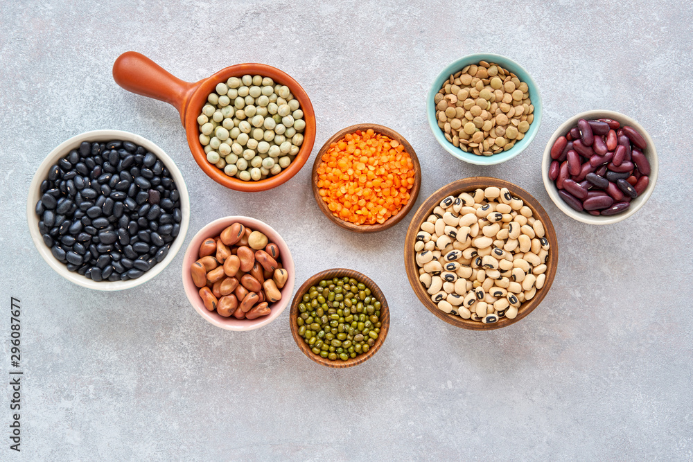 Legumes and beans assortment in different bowls on light stone background . Top view. Healthy vegan protein food. Legumes and beans assortment in different bowls on light stone background . Top view. Healthy vegan protein food.