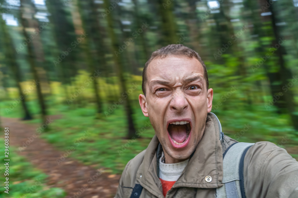 brunette man screaming in the forest in a frightened voice, portrait of a screaming man with his mouth wide open in the autumn forest brunette man screaming in the forest in a frightened voice, portrait of a screaming man with his mouth wide open in the autumn forest