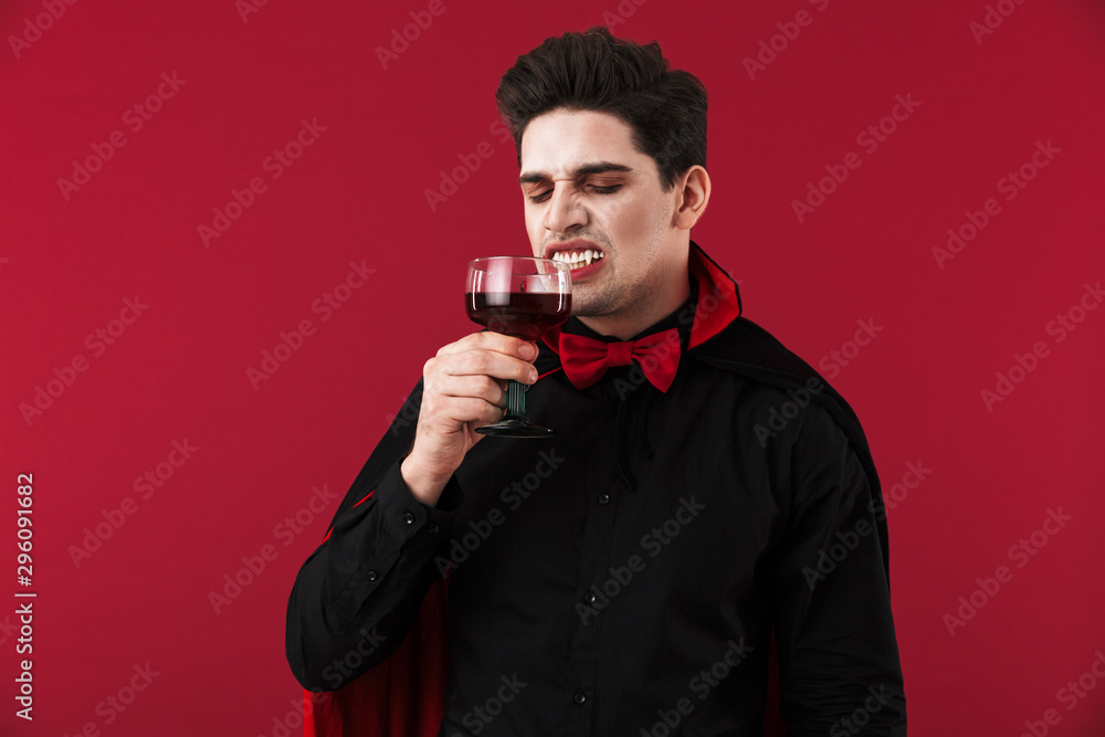 Image of vampire man with fangs in halloween costume drinking blood Image of vampire man with fangs in halloween costume drinking blood