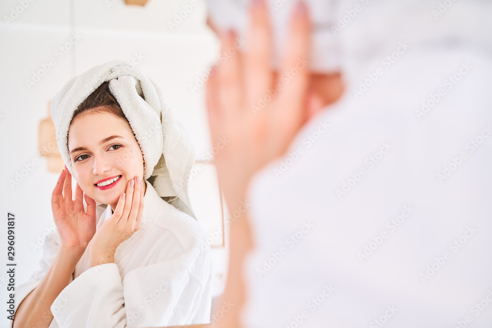Photo of happy woman in bathrobe and with towel on her head reflected in mirror. Photo of happy woman in bathrobe and with towel on her head reflected in mirror.
