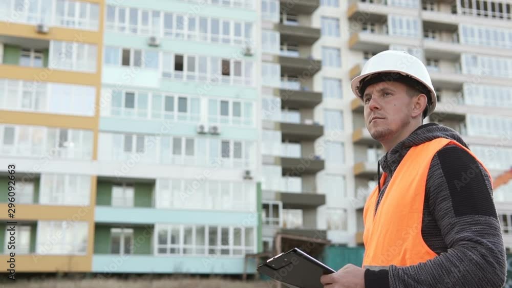 Successful builder engineer stands at construction site in hard hat Successful builder engineer stands at construction site in hard hat