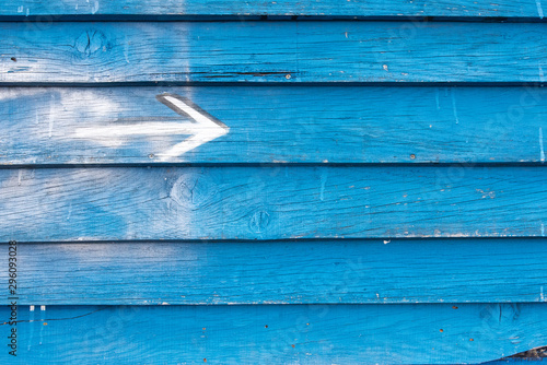 une flèche blanche vers la droite sur un mur de planches bleues  photo