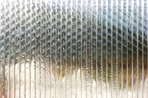 Transparent polycarbonate sheet with morning dew drops. Abstract background.
