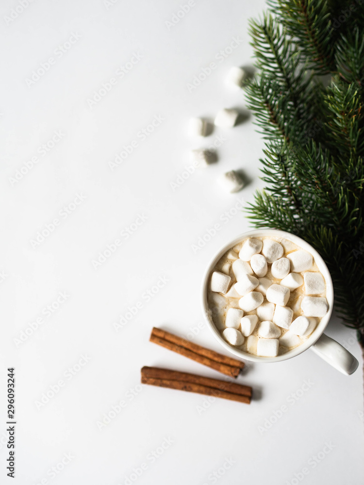 Fototapeta premium White mug with cacao with spices and marshmallows and fir branch on white background. top view. Copy space