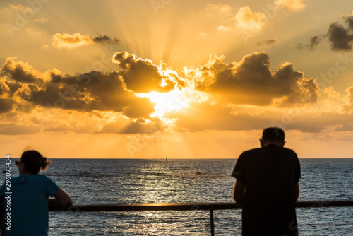 Beautiful sunset and golden twilight, and clouds, Silhouettes of people standing on the coast of Mediterranean sea in Israel and watching the sunset