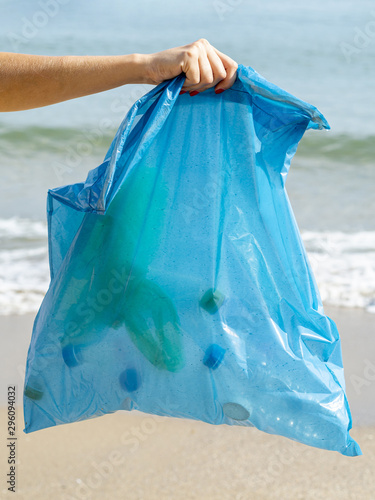 Person holding garbage bag with recyclable plastic bottle