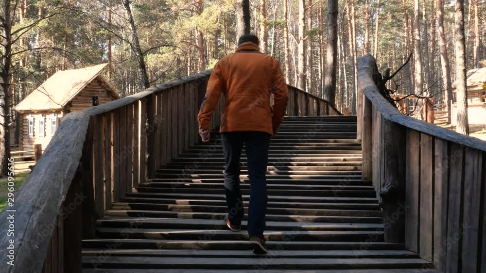 A man crosses a forest river on a wooden bridge. A man crosses a forest river on a wooden bridge.