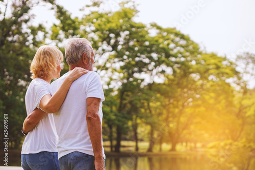 Elderly people couple stood by the lake and looked at the trees.