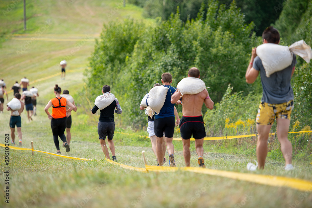 Fototapeta premium Group of people running crossover with heavy bags on their shoulders in summer sunny day