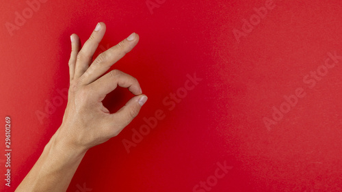 Hand showing ok sign on red background