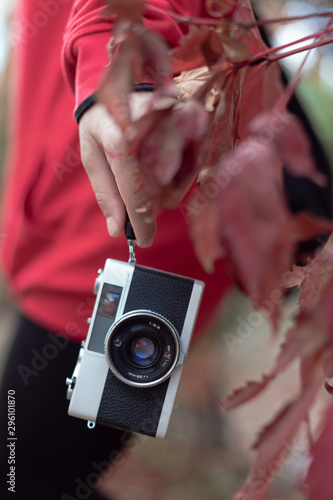 Close-up of a vintage camera hanging on the hand of a girl with the girl in the background