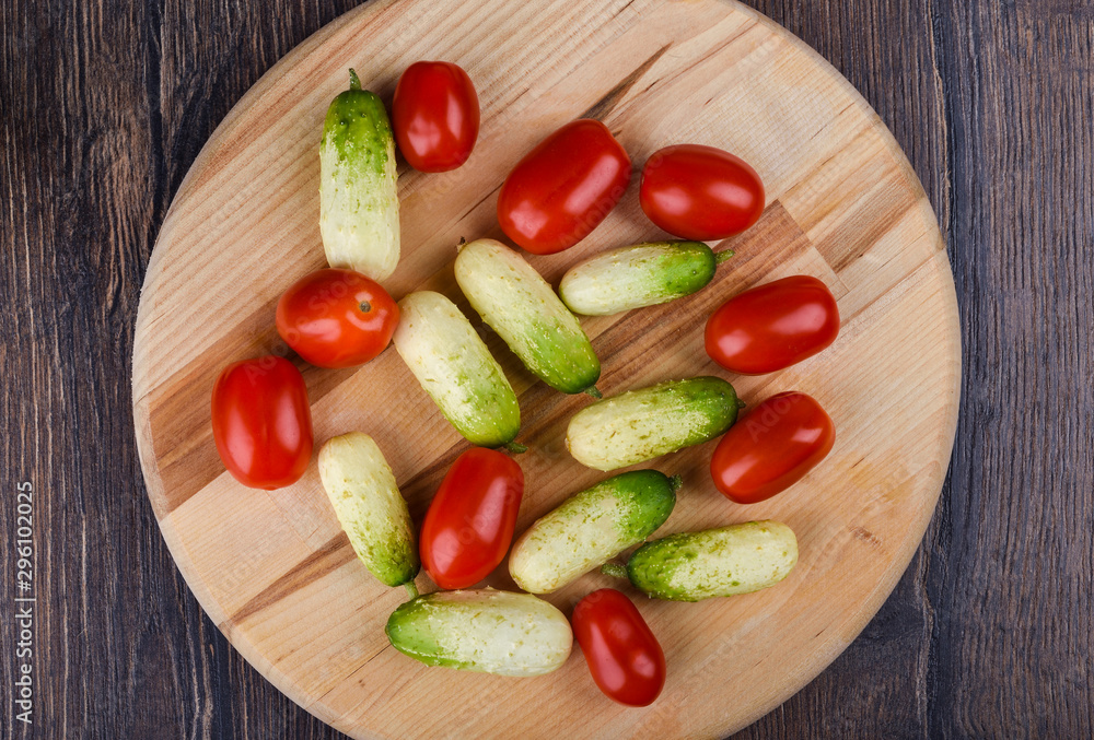 Fresh ripe little cucumbers and cherry tomatoes on a wooden cutting board. Fresh ripe little cucumbers and cherry tomatoes on a wooden cutting board.