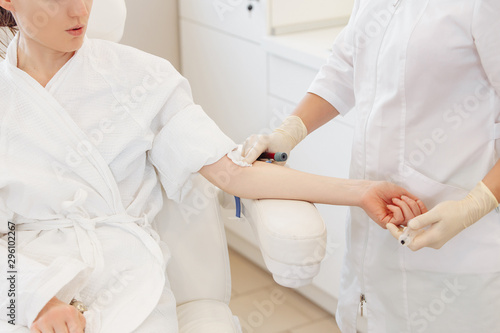 Doctor's hands take blood from a vein from a patient sitting in a chair. Blood test concept and detection of diseases