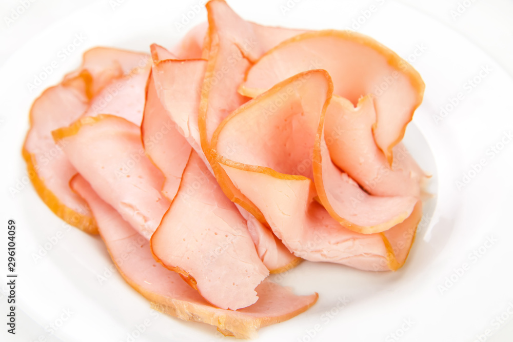 Sliced meat pieces, bacon, cold boiled pork, balyk on a white plate. Isolated on white background. Snack. Meat dish. Closeup