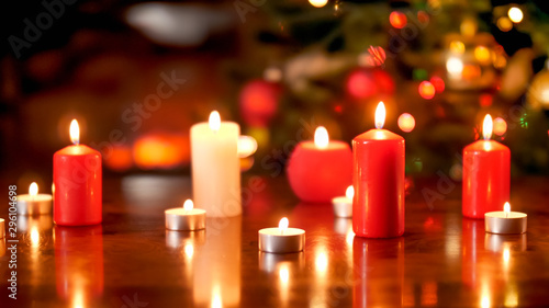 Beautiful Christmas background with burning white and red candles on wooden table