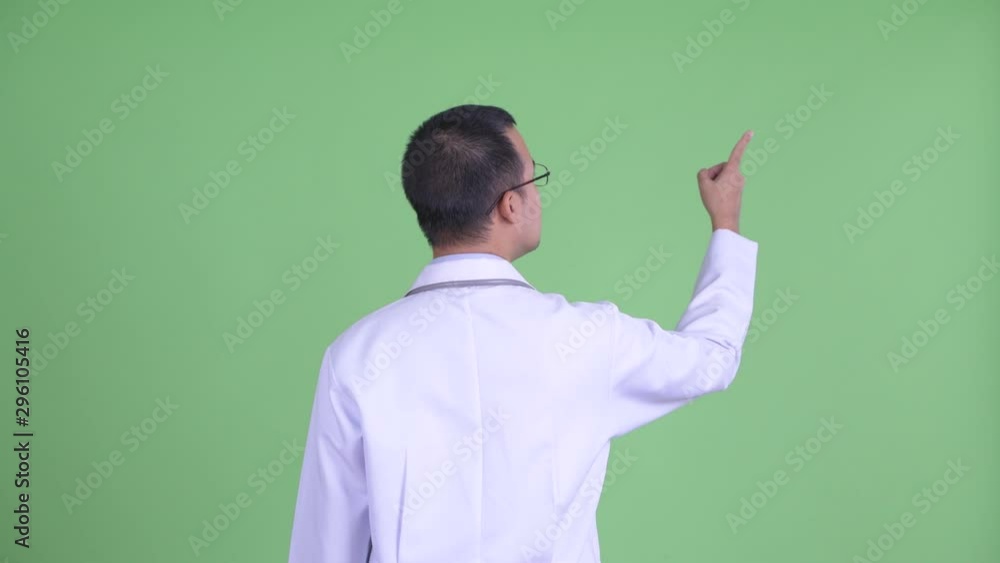 Rear view of Asian man doctor with eyeglasses pointing finger Rear view of Asian man doctor with eyeglasses pointing finger