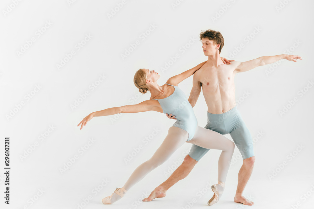 Two young classic ballet dancers practicing against white studio background