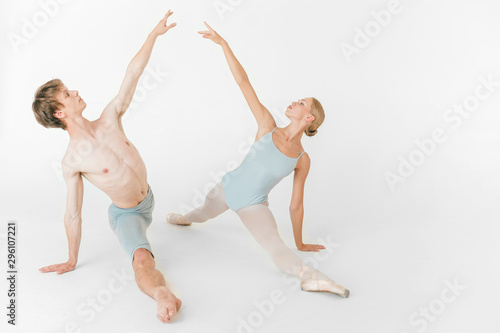 Two young classic ballet dancers practicing against white studio background