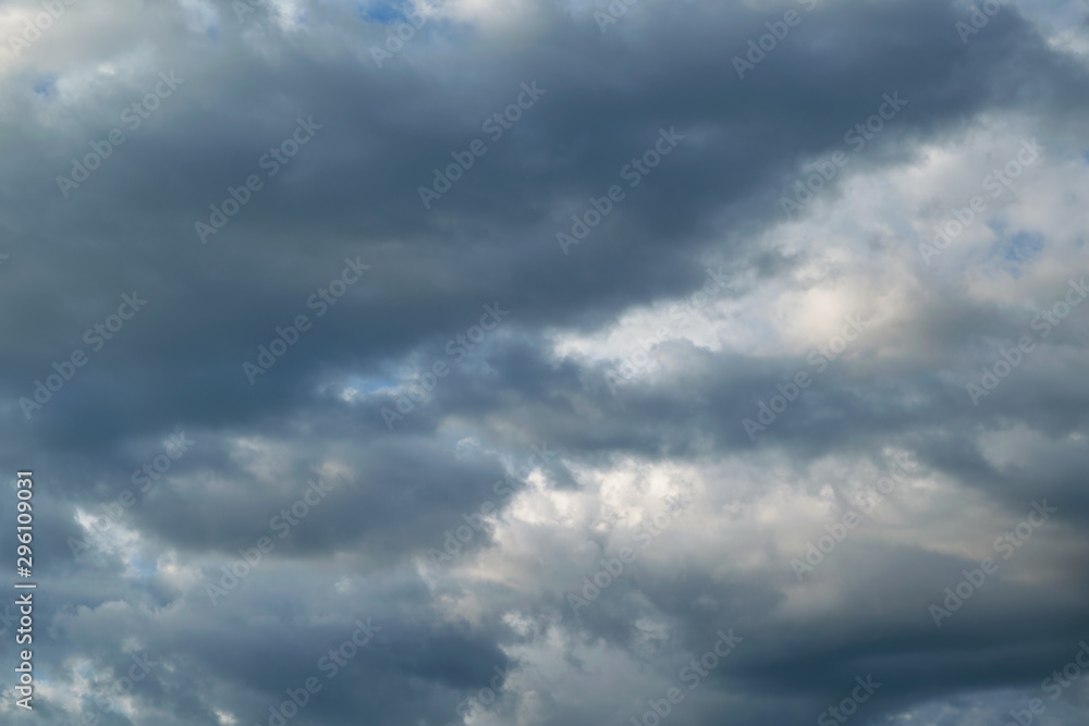 In the sky the storm clouds, and the clouds. Bad weather. Strong wind and feeling the rain. The clouds are dark blue. The clouds are lit by sunlight.