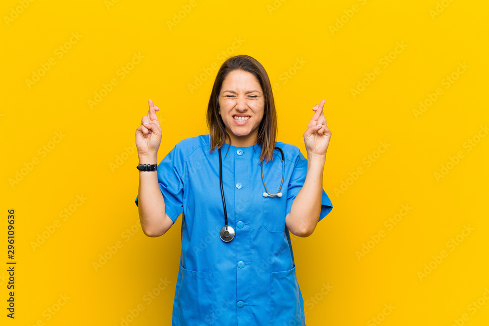 Φωτογραφία smiling and anxiously crossing both fingers, feeling worried and wishing or hopi