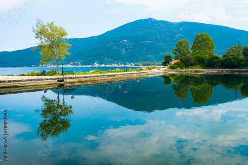 Picturesque view of Karavomilos lake at Sami in Kefalonia ionian island of Greece. Perfect reflection of the claoudscape, the trees and mountain on the calm waters of the lake