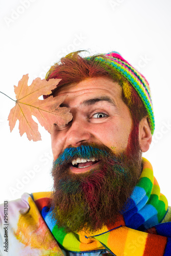 Handsome man with beard. Bearded man holds gold leaf. Autumn clothes for men. Autumn clothes. Color trends for men. Seasonal autumn fashion. Men fashion. Bearded man in trendy colorful scarf and hat.