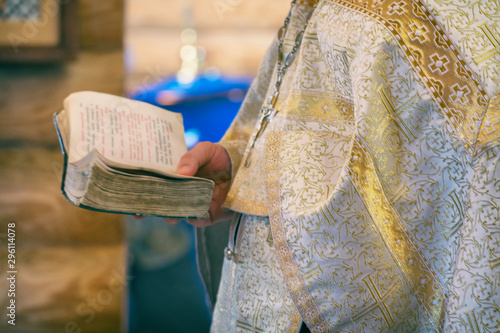 The book is in the hands of a priest or clergyman