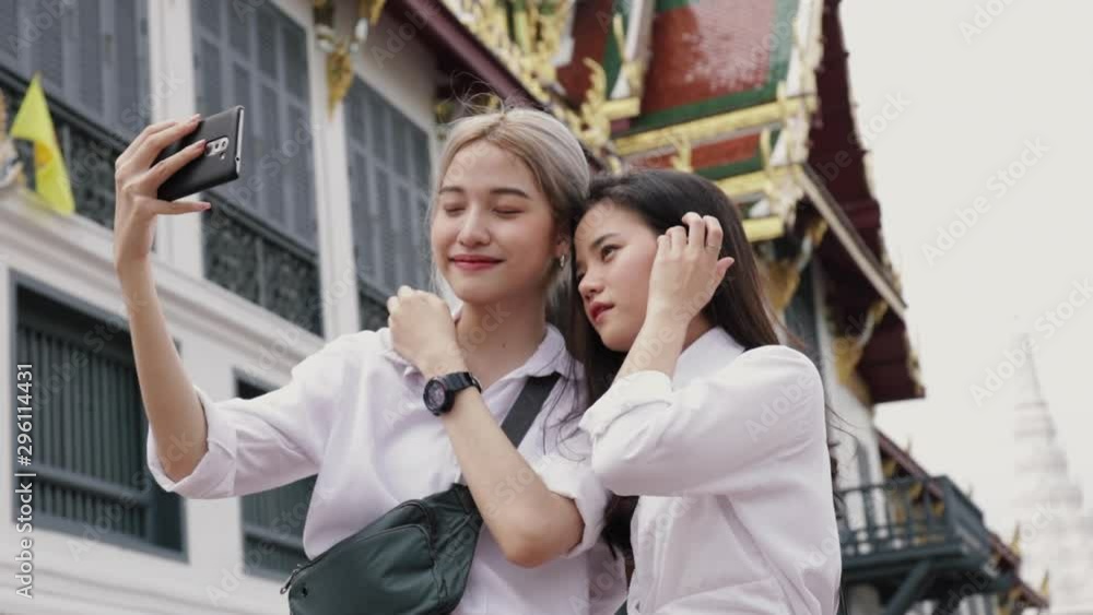 Smiling Asian lesbian couple using smartphones taking selfies a photo. Beautiful Asian women traveling with a friend's vacation lifestyle. Smiling Asian lesbian couple using smartphones taking selfies a photo. Beautiful Asian women traveling with a friend's vacation lifestyle.