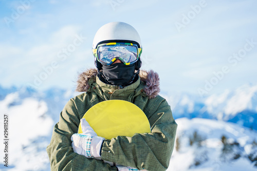 Portrait of man in helmet with snowboard standing on snow resort .