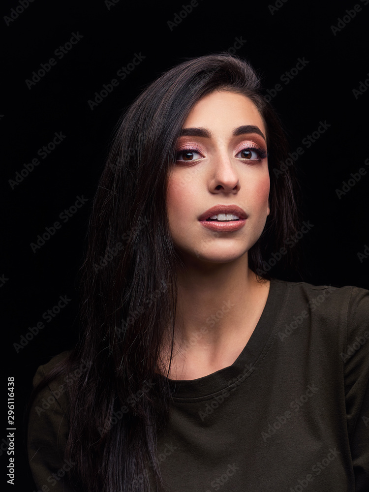 Beautiful young caucasian brunette woman long hair trendy look low key portrait with leucadendron flower black background for makeup artist portfolio in film effect colors Beautiful young caucasian brunette woman long hair trendy look low key portrait with leucadendron flower black background for makeup artist portfolio in film effect colors
