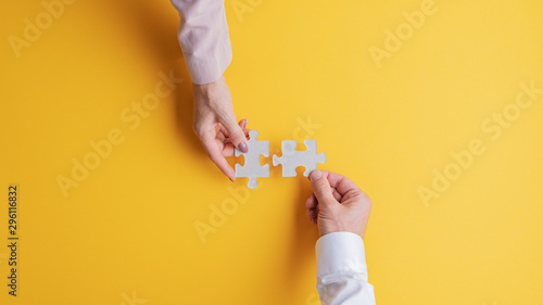 Male and female hands joining two matching puzzle pieces together